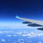 Scenic view of an airplane wing flying high above the clouds on a clear day.